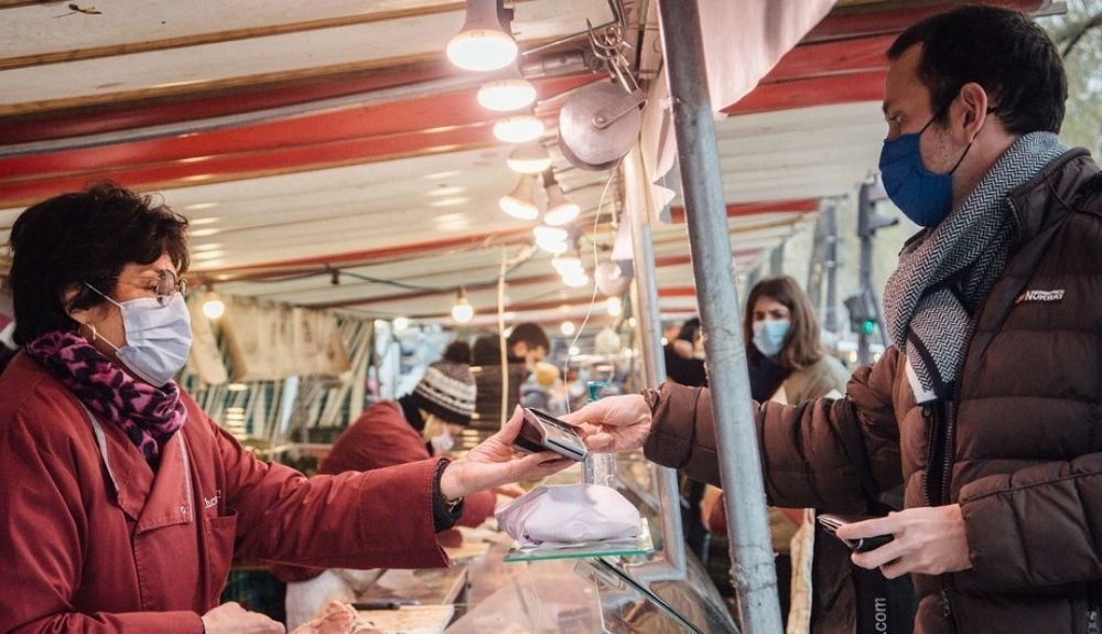Personas con mascarillas contra el COVID 19 en un mercado de París, Francia.