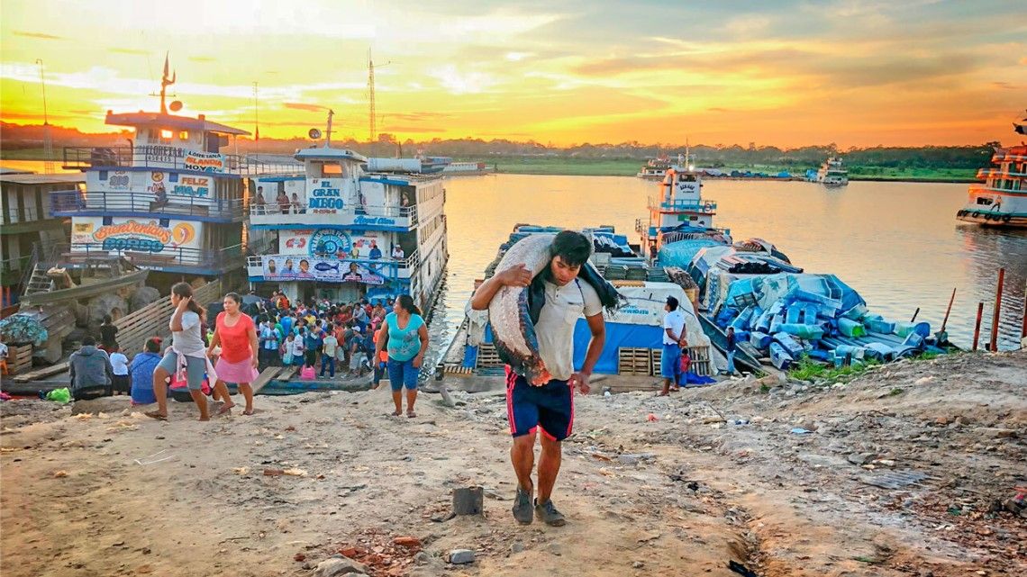 En un puerto del río Amazonas, un hombre lleva un gran pez. Los peces de agua dulce aquí están sufriendo sobrexplotación.