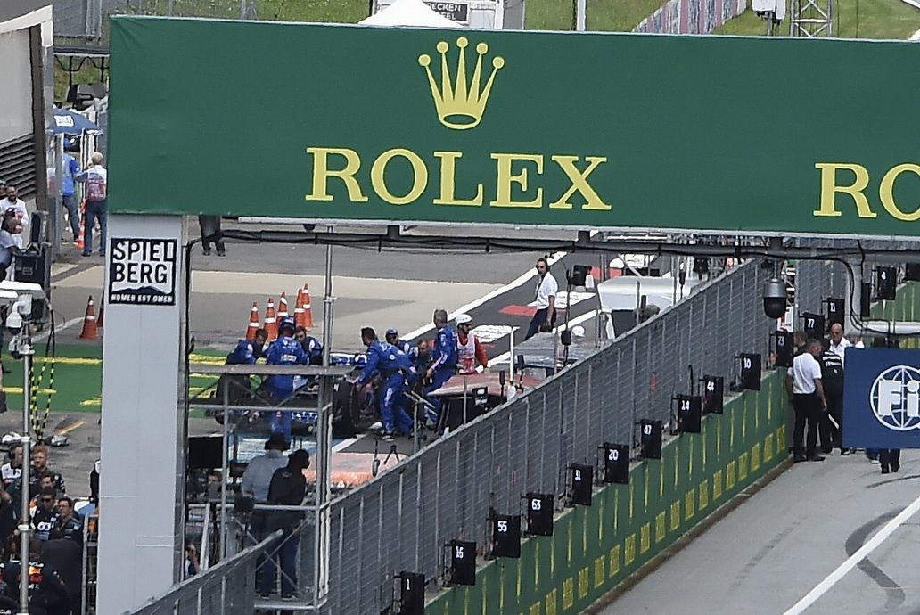 A la izquierda se ve a Fernando Alonso en el pit lane intentando sus mecánicos arrancar el Alpine