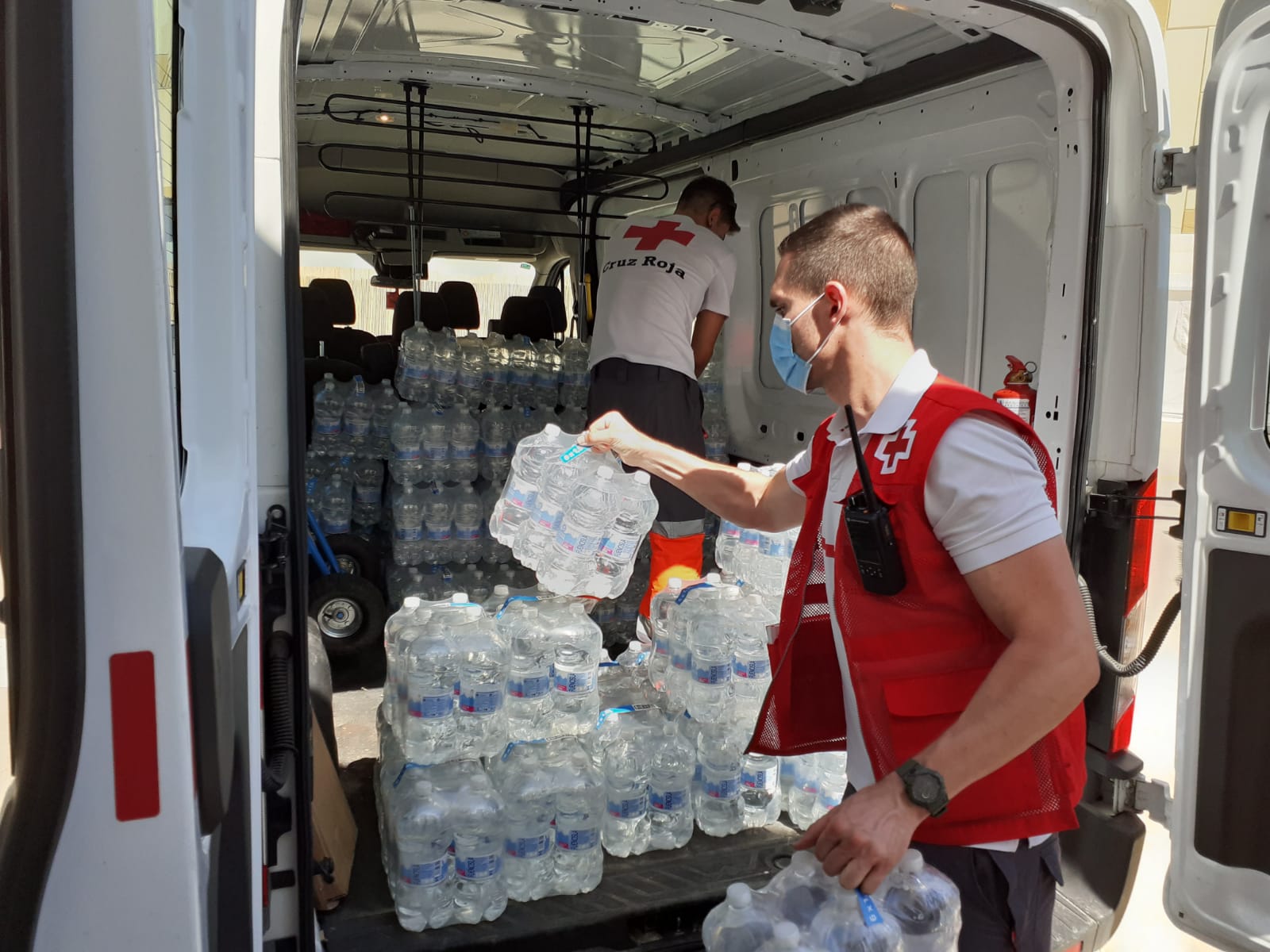 Voluntario de Cruz Roja reparte agua durante una ola de calor en Alicante.