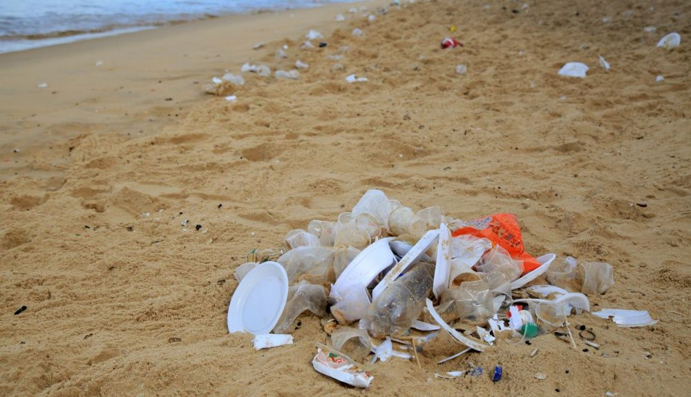 Plásticos de un solo uso acumulados en la arena de la playa. Plásticos de un solo uso acumulados en la arena de la playa.