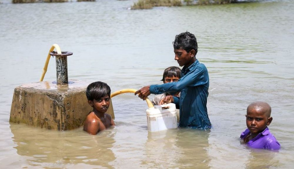 Niños recogen agua potable de una línea de suministro bajo el agua en la inundación en la provincia de Sindh, Pakistán. Niños recogen agua potable de una línea de suministro bajo el agua en la inundación en la provincia de Sindh, Pakistán.