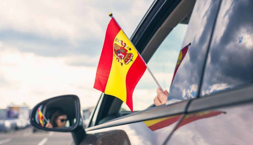Conductor sosteniendo una banderilla española en un coche