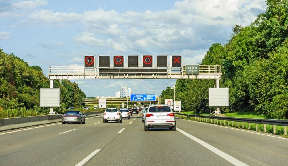 Autopista con una señal luminosa con un aspa roja que indica el cierre temporal de un carril. En España, ignorarlo es infracción grave