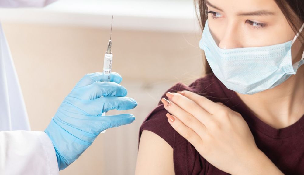Un médico inocua la vacuna a una adolescente.