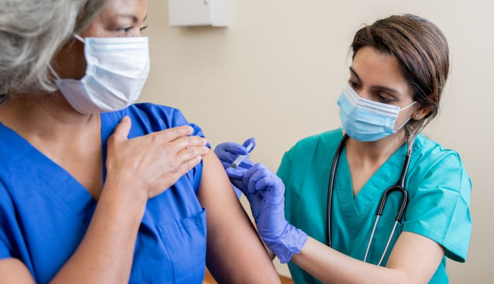 Una enfermera vacuna a una trabajadora de la salud.