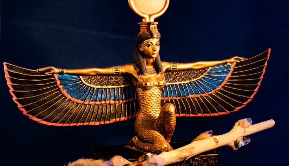 Diosa egipcia Isis arrodillada con la varita mágica tradicional hecha con cuarzo, cristales, madera y pluma Diosa egipcia Isis arrodillada con la varita mágica tradicional hecha con cuarzo, cristales, madera y pluma