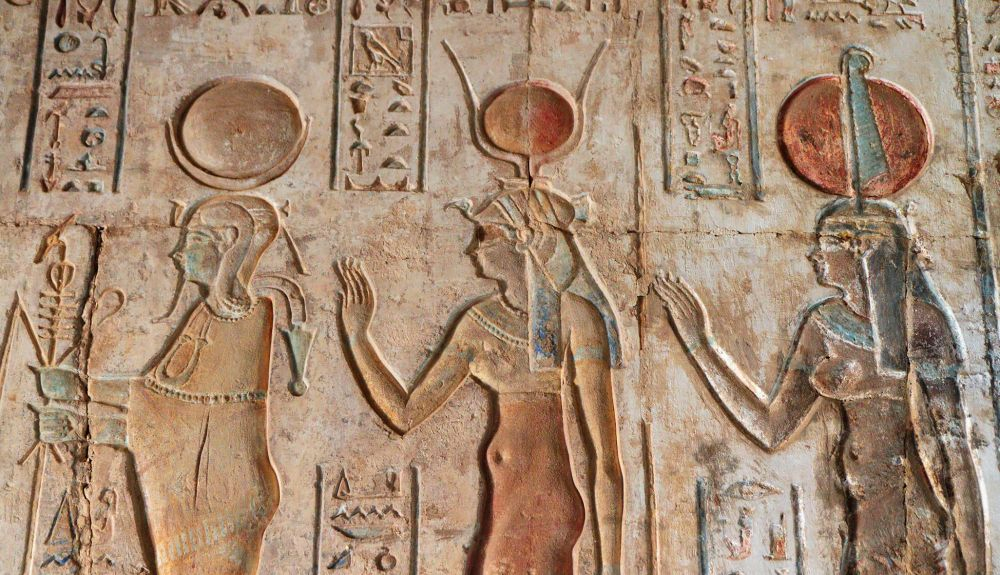 Relievedel templo ptolemaico de Hathor en Deir el Medina. A la izquierda está Osiris, Hathor está en el medio y lleva el disco solar y los cuernos de vaca. La figura de la derecha puede ser Isis. Relievedel templo ptolemaico de Hathor en Deir el Medina. A la izquierda está Osiris, Hathor está en el medio y lleva el disco solar y los cuernos de vaca. La figura de la derecha puede ser Isis.