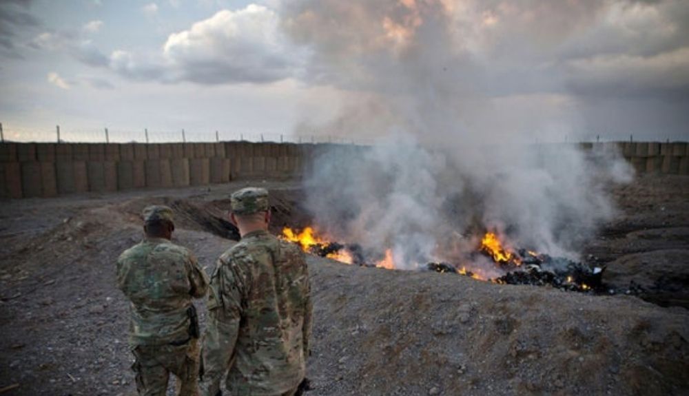 Soldados del Ejército de los Estados Unidos ven cómo arde la basura en un pozo de quemados en la Base de Operaciones Avanzada Azzizulah en Afganistán en febrero de 2013.