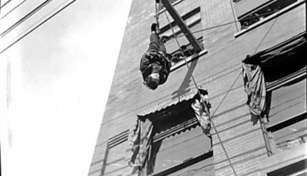 Houdini colgado de un edificio con la camisa de fuerza. Éste fue uno de los números más famosos del mago.