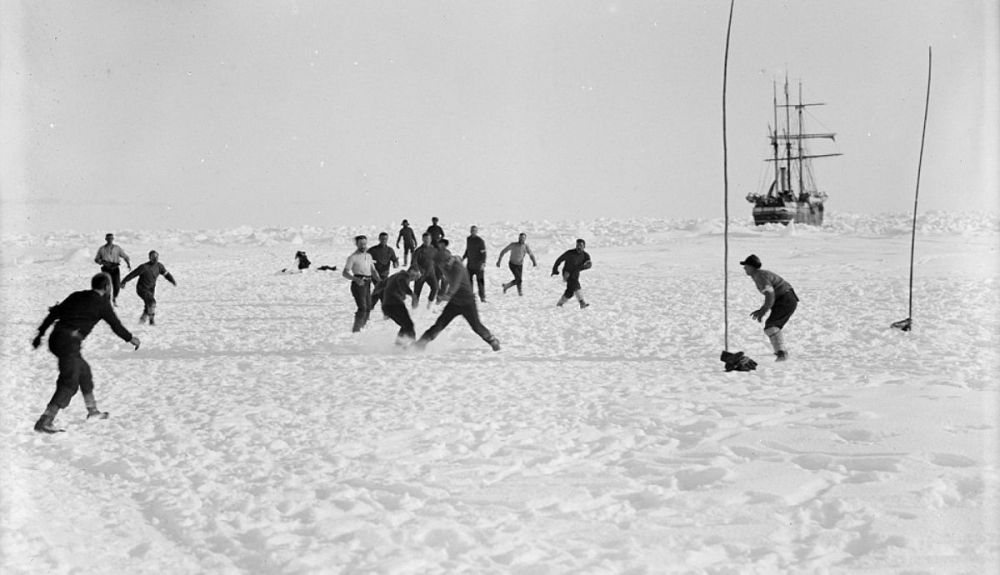 La tripulación, jugando al fútbol en la nieve. Al fondo, el Endurance.
