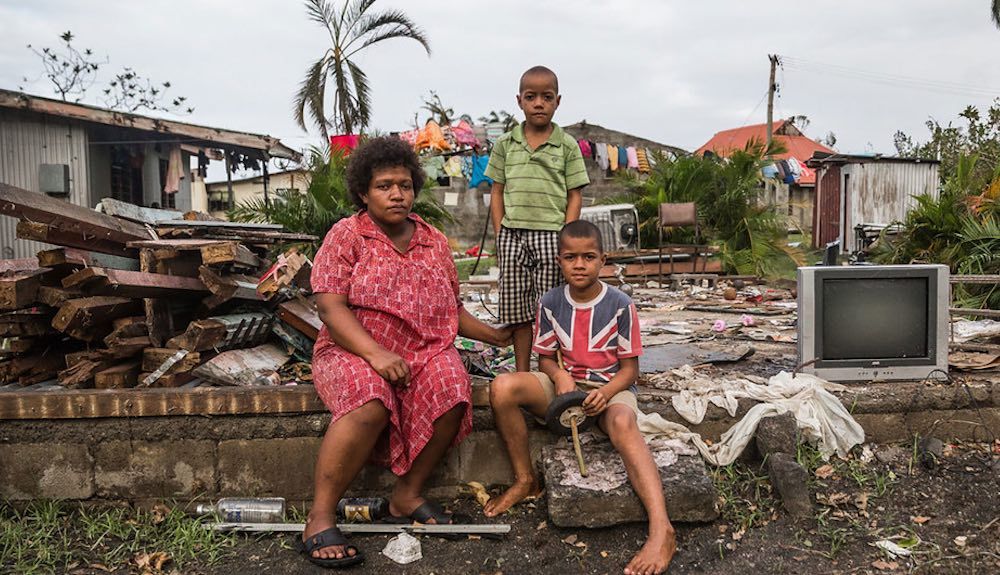 Mereani y sus hijos sentados en una de las paredes de ladrillo de lo que solía ser su hogar en Fiji. Foto: ©UNICEF/Sokhin 