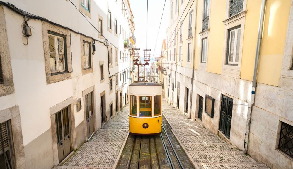 Famoso tranvía de funicular amarillo retro en calles estrechas del casco antiguo de Lisboa en un soleado día de verano. Famoso tranvía de funicular amarillo retro en calles estrechas del casco antiguo de Lisboa en un soleado día de verano.