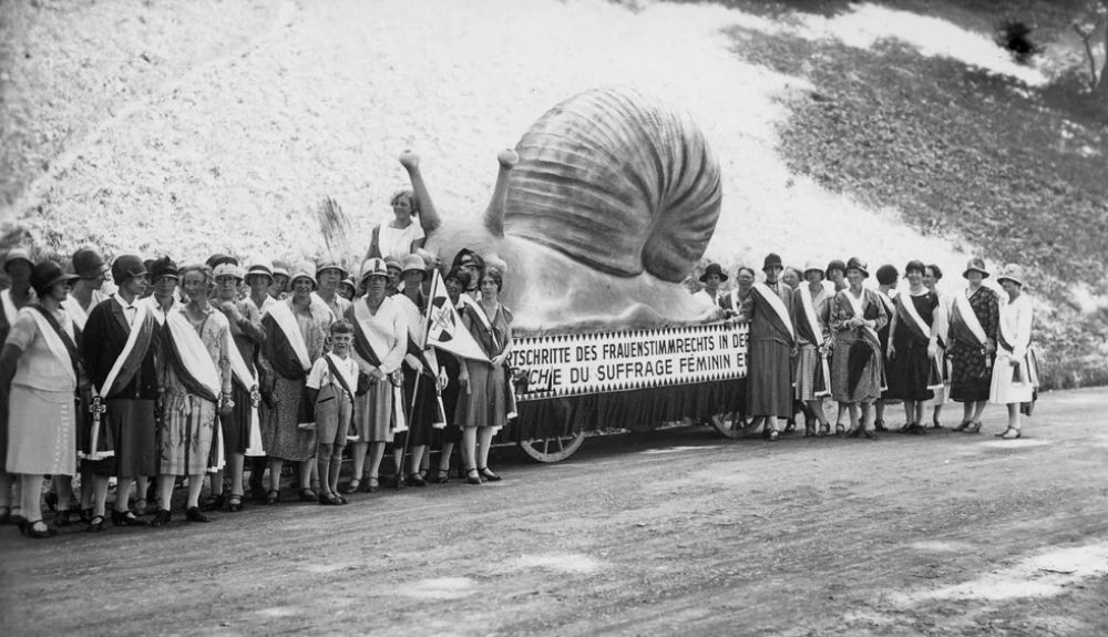Mujeres protestando en 1920 por la falta de sufragio con un caracol gigante, que representa la demora en otorgarles el voto. Mujeres protestando en 1920 por la falta de sufragio con un caracol gigante, que representa la demora en otorgarles el voto.